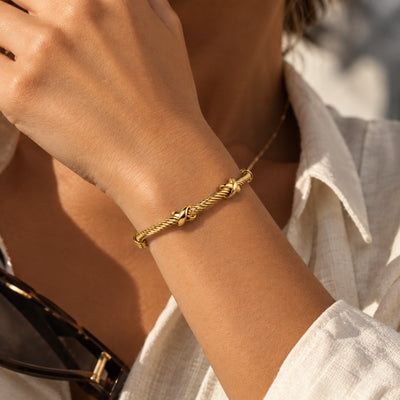Two Hearts Cuff — Gold-tone twisted cuff with heart motifs (close-up detail)