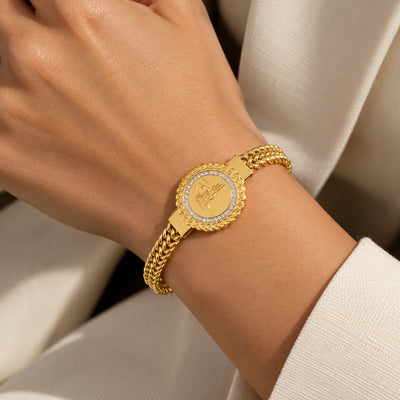Monogram Charm Bracelet — Round engraved charm with a pave-set border on a braided gold-tone chain (close-up detail)